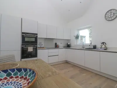 a kitchen with white cabinets and a clock on the wall at Kerrek Lodge in Falmouth
