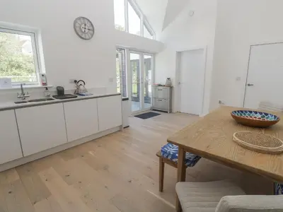a kitchen with white cabinets and a wooden table at Kerrek Lodge in Falmouth