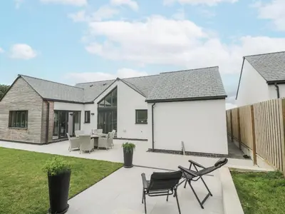 a detached house with a white facade and black chairs at Kerrek Lodge in Falmouth