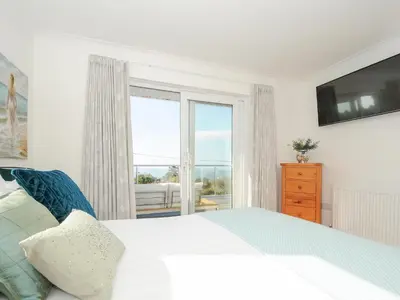 a bedroom with a white bed and a large window at Atlanta in Tintagel