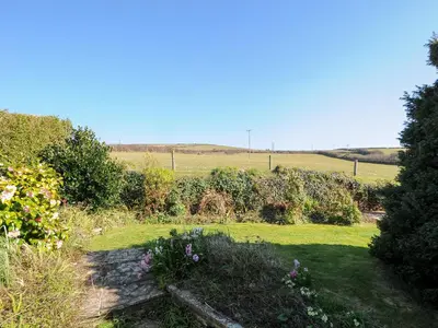 a garden with flowers and a field in the background at Atlanta in Tintagel