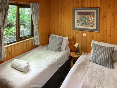 two beds in a room with wooden walls at The Hut Hotel in Falmouth