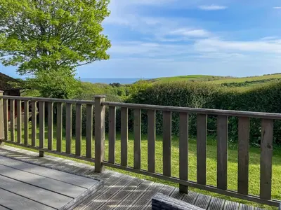 a wooden deck with a view of the green hills at The Hut Hotel in Falmouth