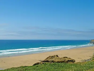 a beach with a large rock and the ocean at Tide & Treth in Newquay