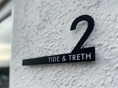 a sign on the side of a white building at Tide & Treth in Newquay