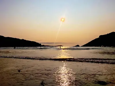 a sunset on a beach with the sun setting at Tide & Treth in Newquay