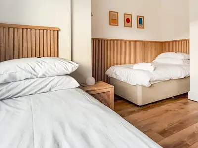 two beds in a room with wooden floors at Tide & Treth in Newquay