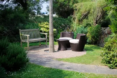 a park bench and three trash cans in a garden at Cliff House, Cornwall in Padstow