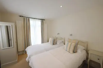 two white beds in a room with a window at Cliff House, Cornwall in Padstow