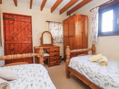 a bedroom with two beds and a dresser and a mirror at Carolyns Cottage in Penzance