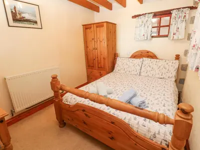 a bedroom with a wooden bed in a room at Carolyns Cottage in Penzance