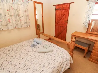 a bedroom with a bed and a dresser and a mirror at Carolyns Cottage in Penzance