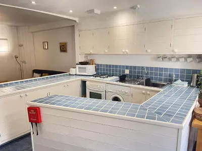 a kitchen with white cabinets and blue tiles at Chy Meor - a stonesthrow away from Porthmeor Beach in St Ives