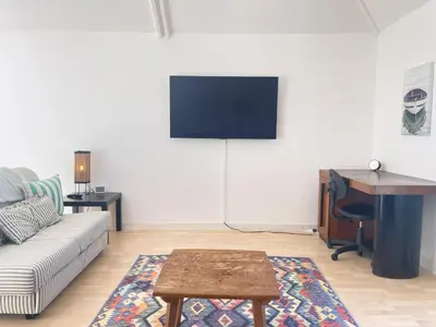 a living room with a couch and a desk and a tv at Chy Meor - a stonesthrow away from Porthmeor Beach in St Ives