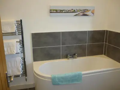 a bathroom with a bath tub with a picture on the wall at The Barn At Collacott in North Petherwin