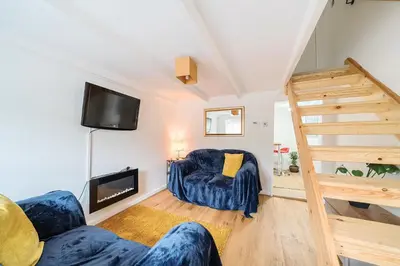 a living room with a staircase and a couch and a television at Charming Chardan Cottage, Fowey in Fowey