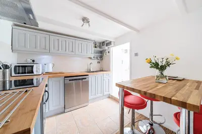 a kitchen with white cabinets and a wooden counter top at Charming Chardan Cottage, Fowey in Fowey
