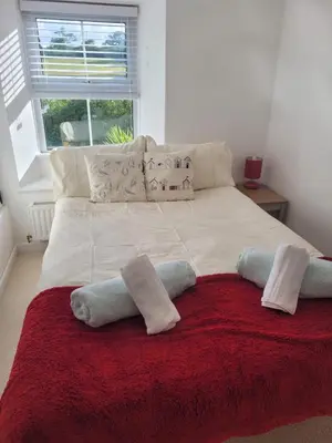 a large white bed with pillows and a red blanket at Charming Chardan Cottage, Fowey in Fowey