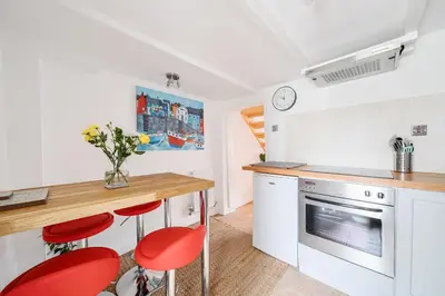 a kitchen with a counter and red stools in it at Charming Chardan Cottage, Fowey in Fowey
