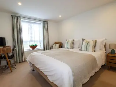 a white bedroom with a large bed and a window at 4 Ocean Gate in Newquay