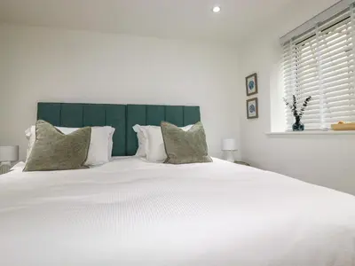 a white bed with white pillows and a green headboard at 4 Ocean Gate in Newquay
