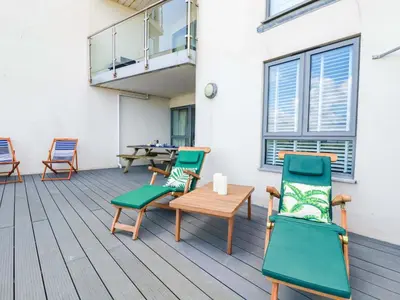 a deck with chairs and a table and a table and chairs at 4 Ocean Gate in Newquay