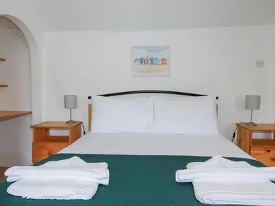 a bedroom with a bed with white sheets and towels at Pennine in Truro