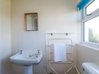 a white bathroom with a sink and a mirror at Pennine in Truro