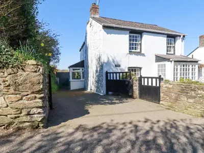 a white house with a gate and a stone wall at Pennine in Truro