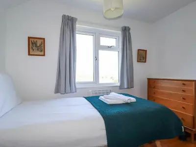 a bedroom with a bed with a blue blanket and a window at Pennine in Truro