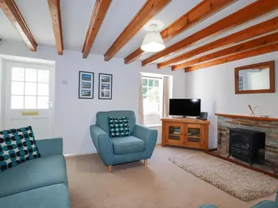 a living room with a tv and a couch and a chair at Pennine in Truro