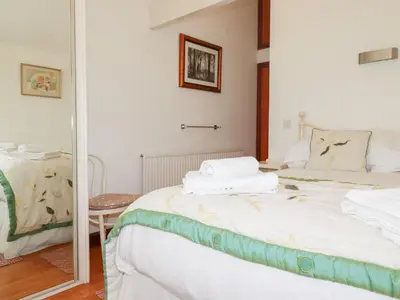 a bedroom with a bed with white sheets and a mirror at Rosemaddon in Newquay
