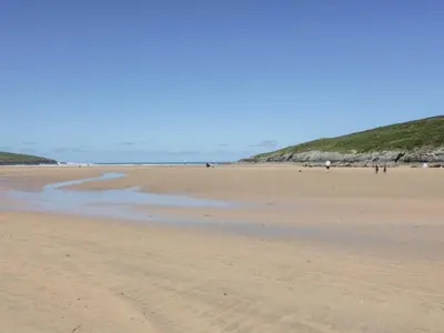a beach with people walking on the sand at Rosemaddon in Newquay