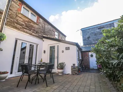 a patio with a table and chairs in front of a house at Mews Cottage in Tintagel