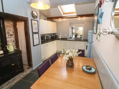 a kitchen with a wooden table with flowers on it at Mews Cottage in Tintagel