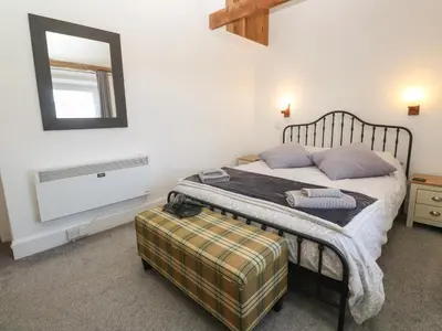 a bedroom with a bed and a mirror on the wall at Mews Cottage in Tintagel