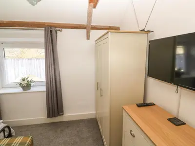 a room with a tv and a desk and a window at Mews Cottage in Tintagel