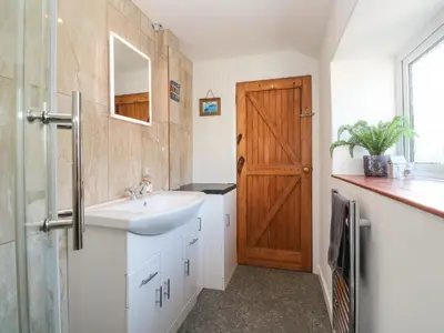 a bathroom with a sink and a wooden door at Mews Cottage in Tintagel