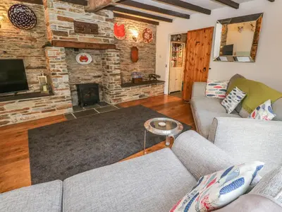 a living room with two couches and a fireplace at Mews Cottage in Tintagel
