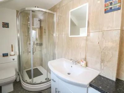 a bathroom with a shower and a sink and a toilet at Mews Cottage in Tintagel