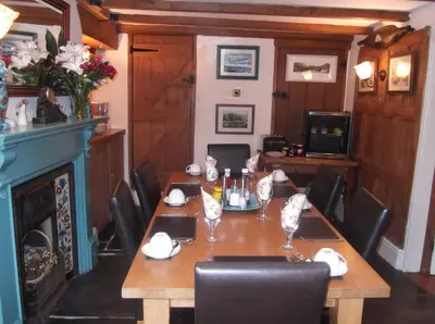 a dining room with a table with chairs and a fireplace at Culloden Farmhouse in Camelford