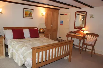 a bedroom with a bed and a desk and a chair at Culloden Farmhouse in Camelford