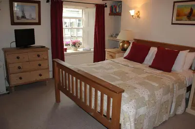 a bedroom with a bed and a television and a window at Culloden Farmhouse in Camelford