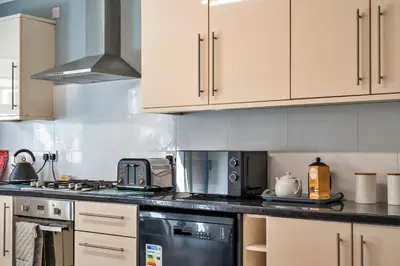 a kitchen with white cabinets and a stove top oven at Finest Retreats - No 5 Harlequin in St Ives