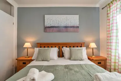 a bedroom with a bed and two lamps and a painting at Finest Retreats - No 5 Harlequin in St Ives