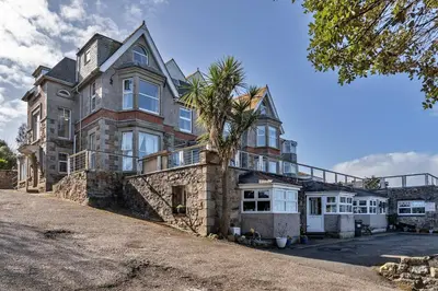 a large house with a palm tree in front of it at Finest Retreats - No 5 Harlequin in St Ives