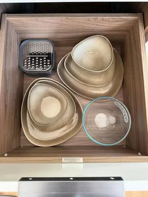 a drawer filled with plates and a remote control at Acorn Lodge Pentewan in St Austell