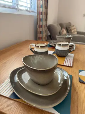 a wooden table with three plates and a bowl on it at Acorn Lodge Pentewan in St Austell