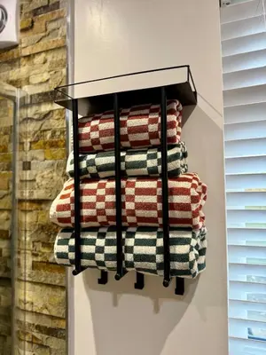 a stack of towels on a towel rack on a wall at Acorn Lodge Pentewan in St Austell