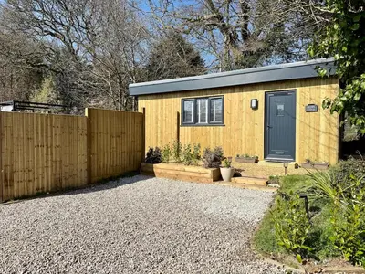a yellow tiny house with a blue door at Acorn Lodge Pentewan in St Austell